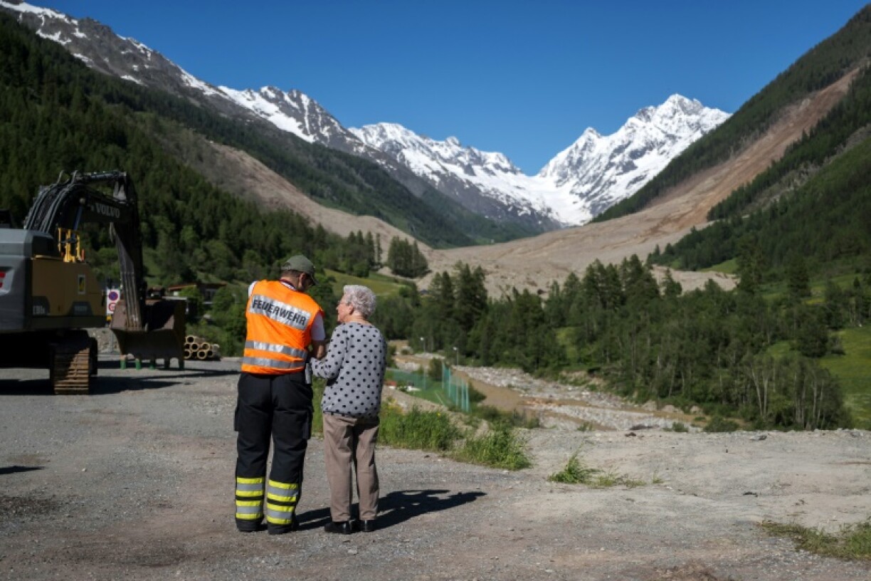 A firefighter shows a woman the area affected by a massive landslide in the Lotschental valley