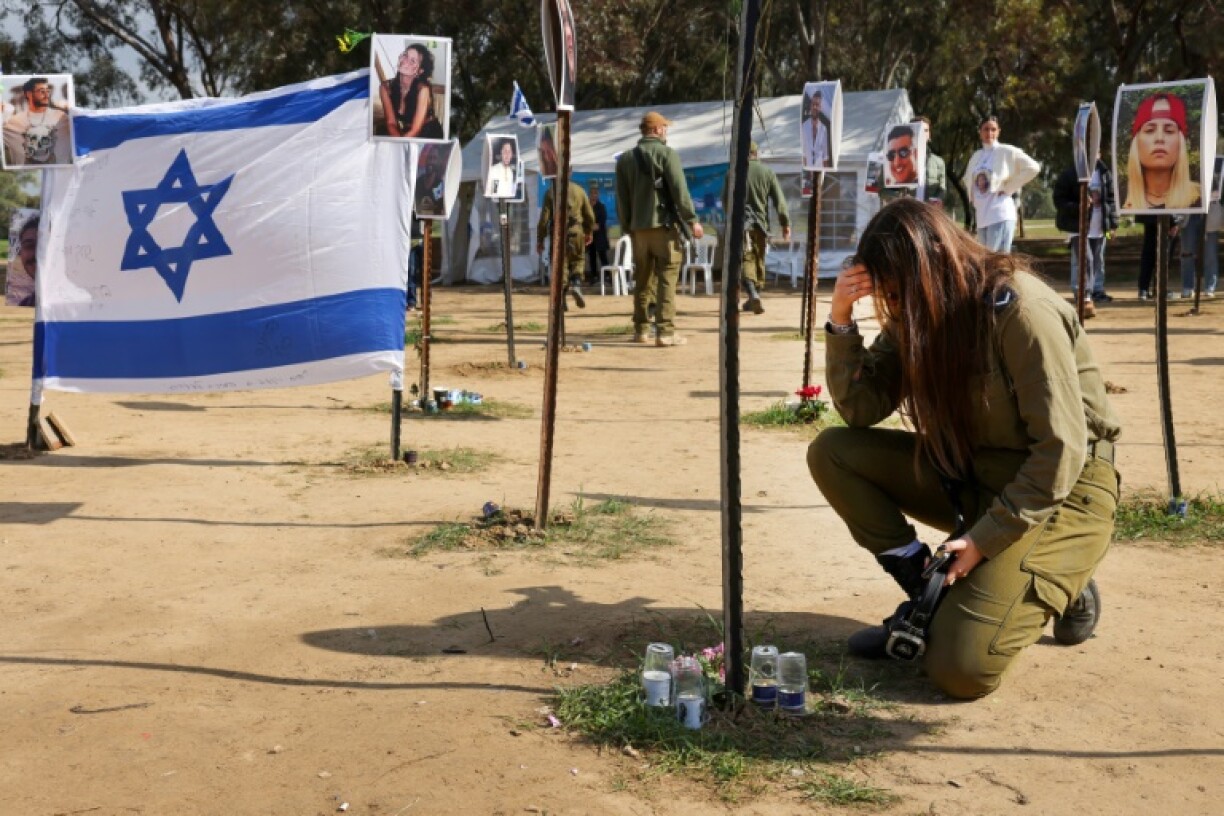 Un soldat israélien se recueille devant des photos de personnes capturées ou tuées par des militants du Hamas lors du festival de musique Supernova le 7 octobre, sur le site où l'attaque meurtrière a eu lieu, près du kibboutz Reim, dans le sud d'Israël, le 5 janvier 2024