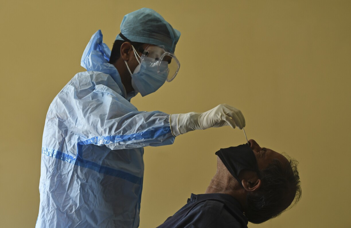 A medical worker collects a swab sample from a staff member of the Burnhall school inside a classroom for a Rapid Antigen Test (RAT) for the Covid-19 coronavirus, in Srinagar on October 5, 2020.