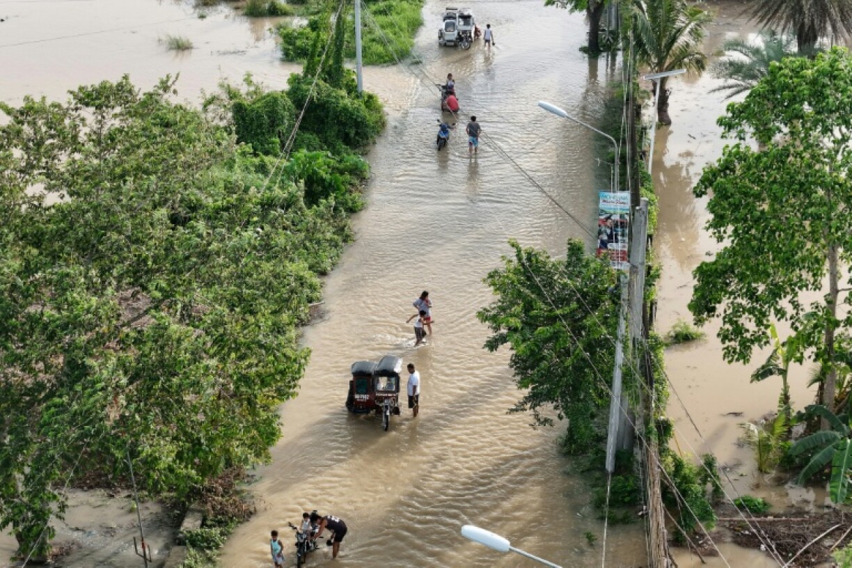 People wade through the water along a submerged street in Tuguegarao City in the Philippines' Cagayan province