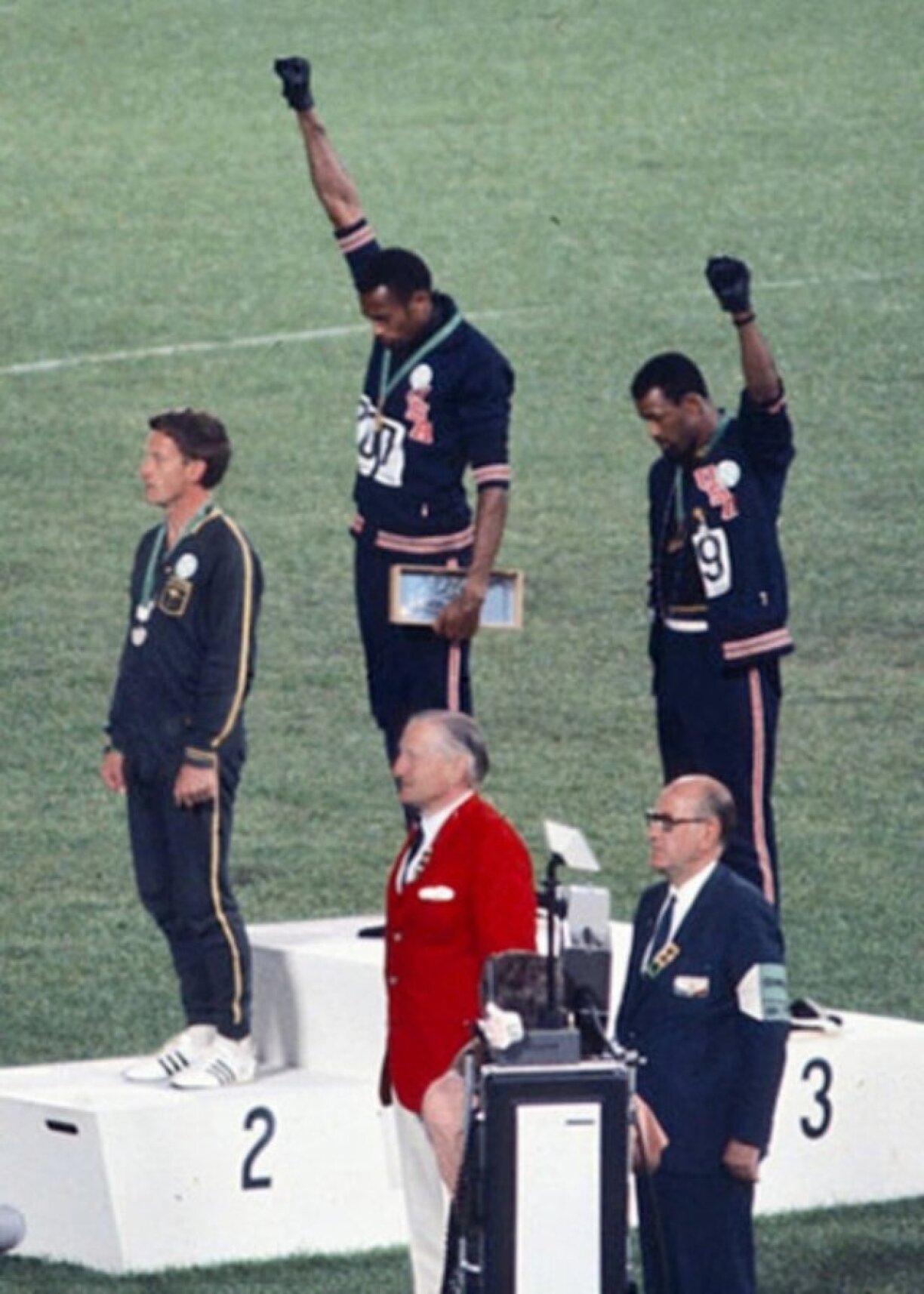 Den Tommie Smith (Mëtt), John Carlos (riets) a Peter Norman (lénks) bei den olympesche Spiller 1968,