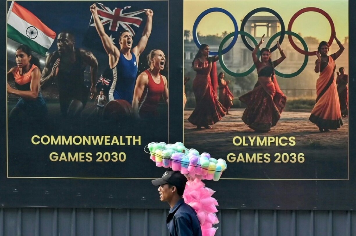 A cotton candy seller walks past a billboard in Ahmedabad