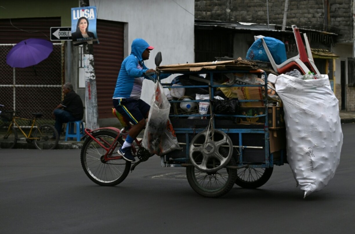 A recycler rides his tricycle in front of a campaign poster of Ecuador's leftist candidate Luisa Gonzalez in Guayaquil