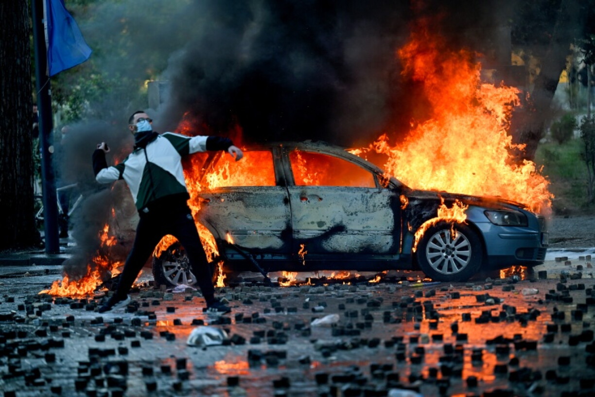 A protester throws a cobblestone during an anti-government demonstration in central Tirana on October 17, 2026, as protests continued for a fifth consecutive day over university conditions and demands for the resignation of Albanian Prime Minister. Several hundred people, some masked, gathered around noon in front of the ministry of education, with protests later spreading across the city. Protesters threw rocks at the police and set litter bins on fire, using them as barricades to prevent the police from advancing.