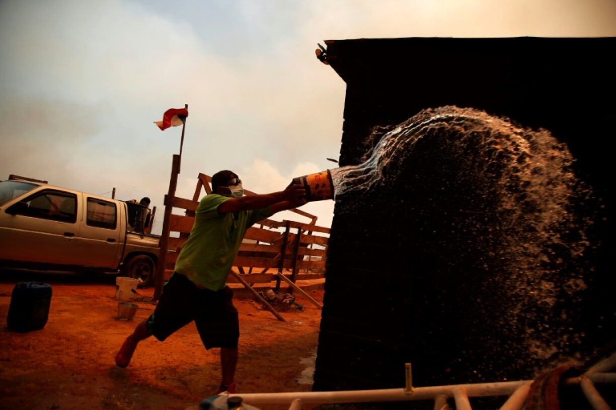 Un homme lutte contre les flammes le 3 février 2024 à Quilpé dans la région de Valparaiso au Chili en proie à des feux de forêt