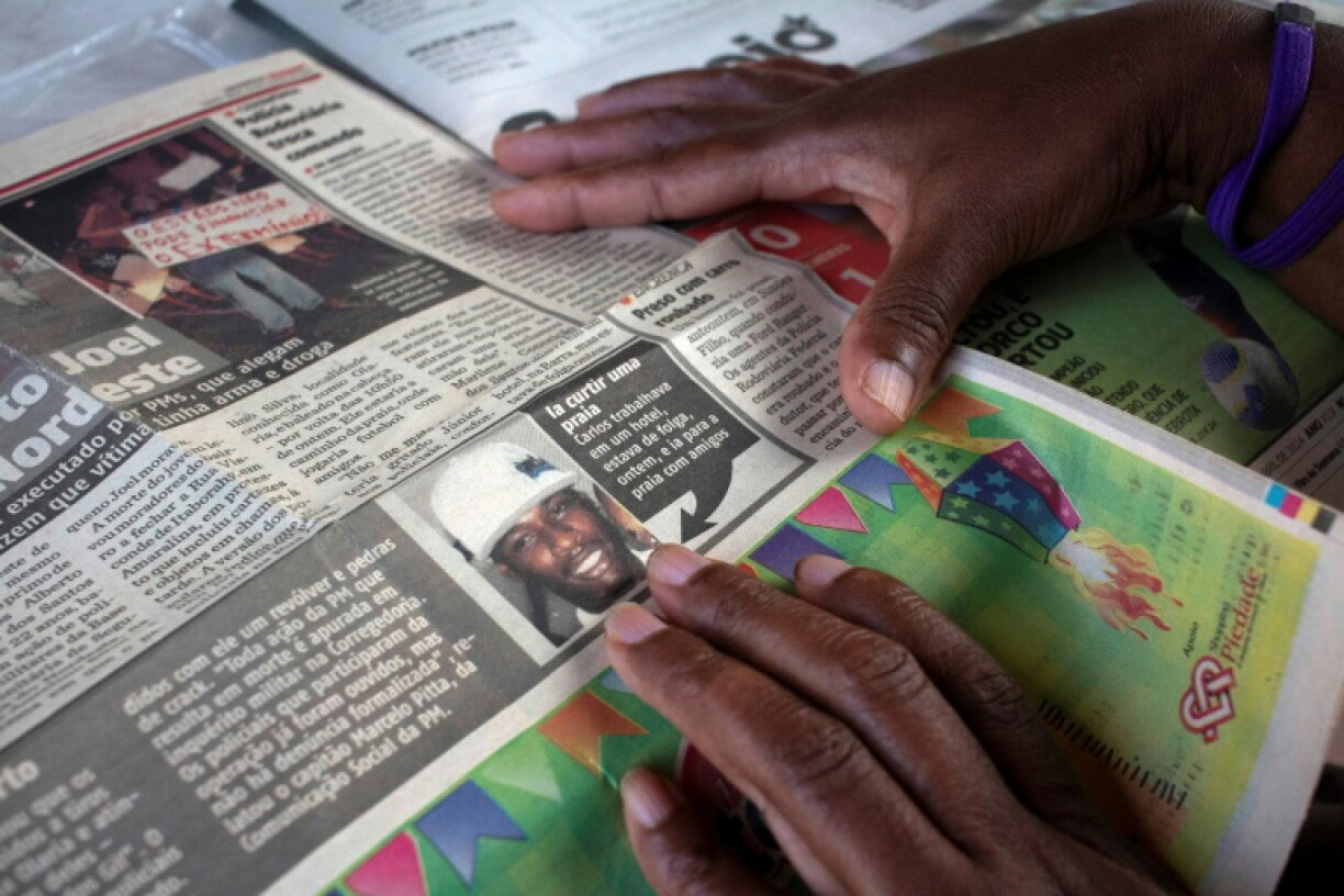 Rita Cassia, the mother of Carlos Alberto, shows a newspaper clipping reporting the killing of her son during a police operation in 2013