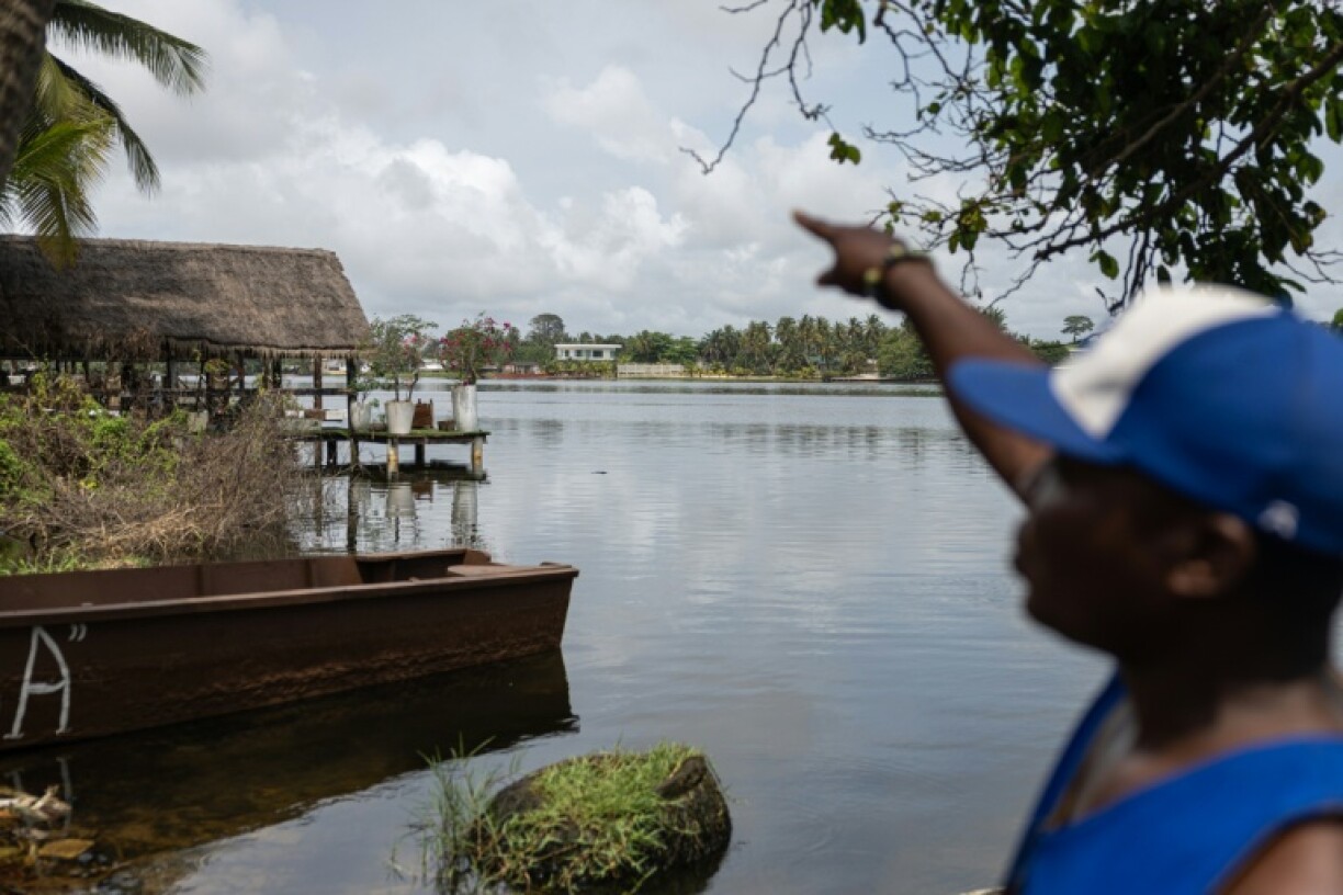 Local tour guide Pierre Ake gestures toward luxury properties overlooking the lagoon which now attracts Abidjan's wealthiest