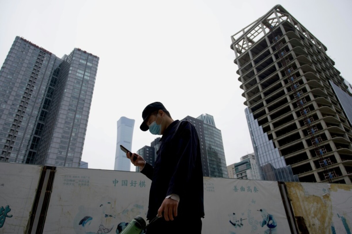 Un passant consulte son smartphone dans une rue de Pékin, le 9 mai 2022