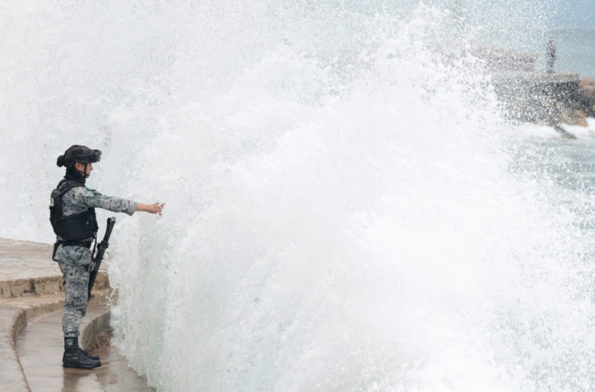 A member of Mexico's National Guard stands on the Puerto Vallarta boardwalk as waves crash against the shoreline