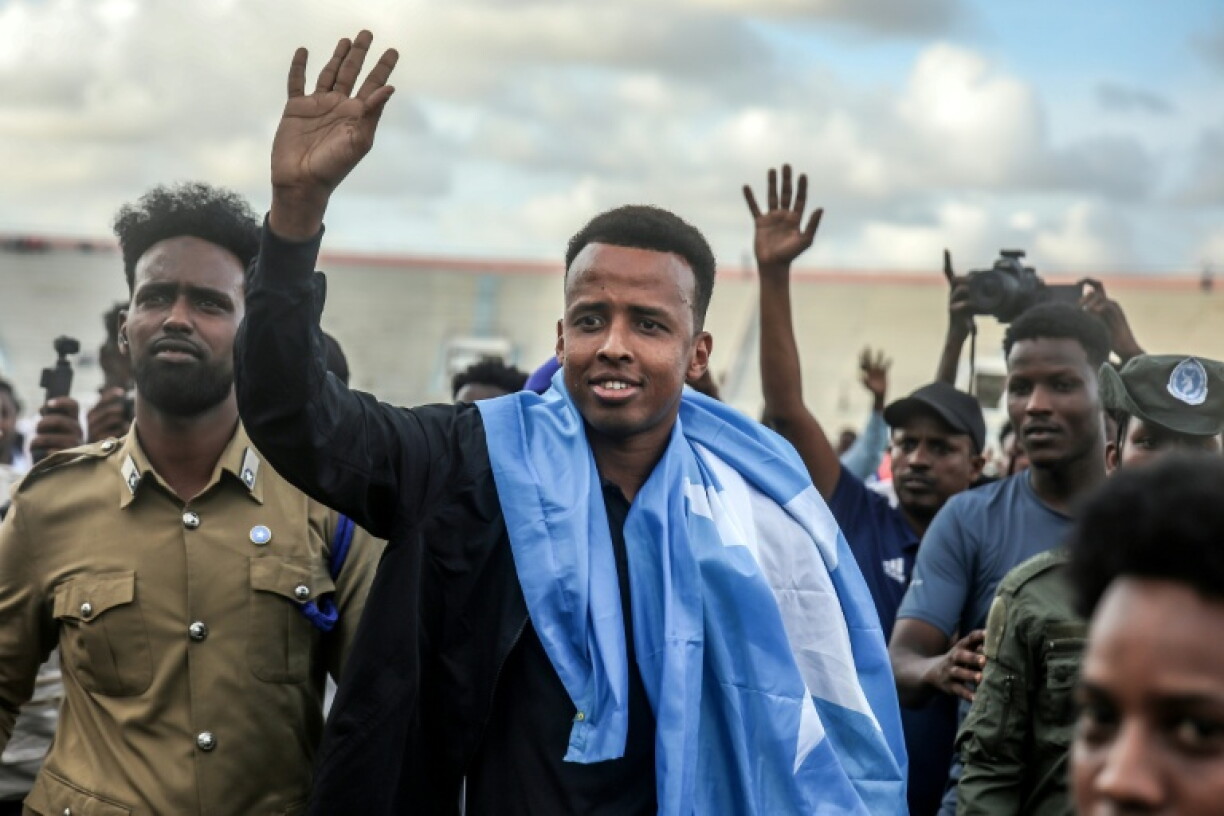 L'arbitre somalien Omar Artan salue ses supporters, drapé dans le drapeau national, lors de l'accueil qui lui est réservé avant un match de football de solidarité à son retour en Somalie, le 10 juin 2026 à Mogadiscio