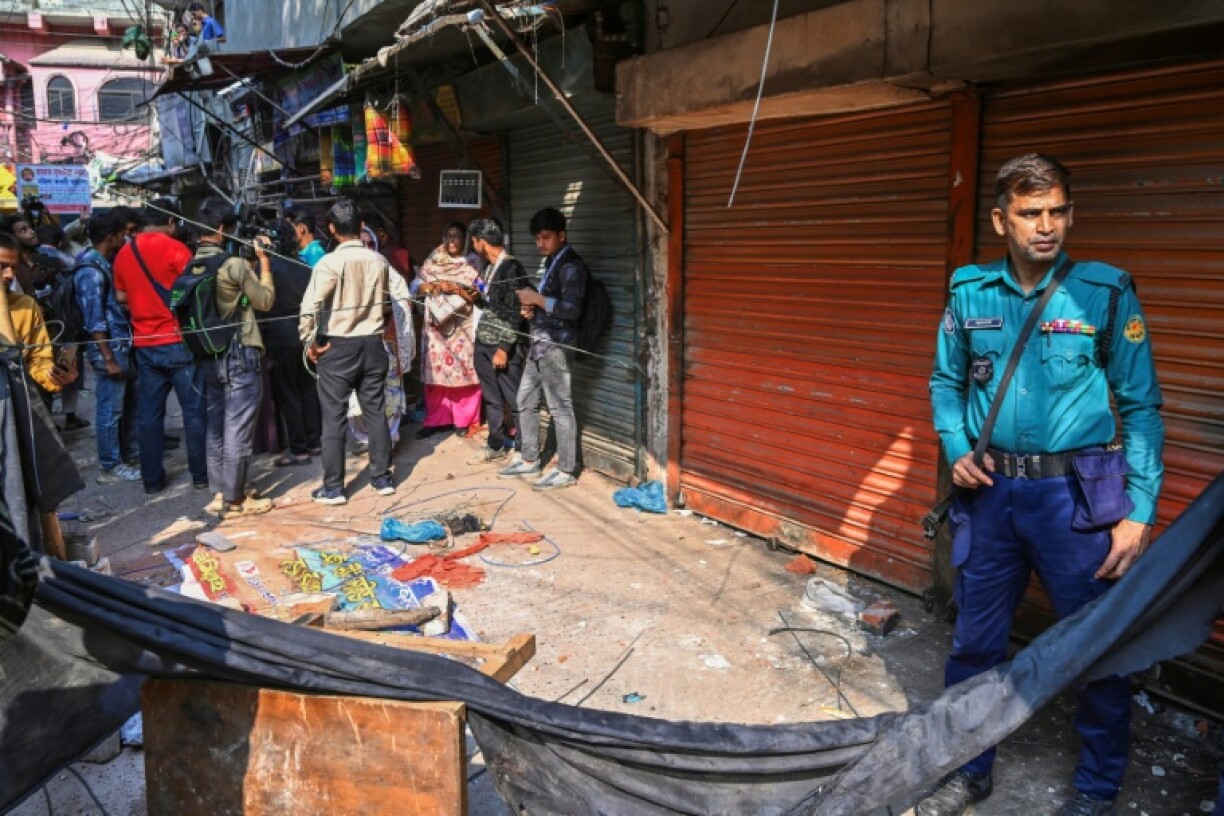 Police near rubble that fell from a damaged building following an earthquake, in Dhaka