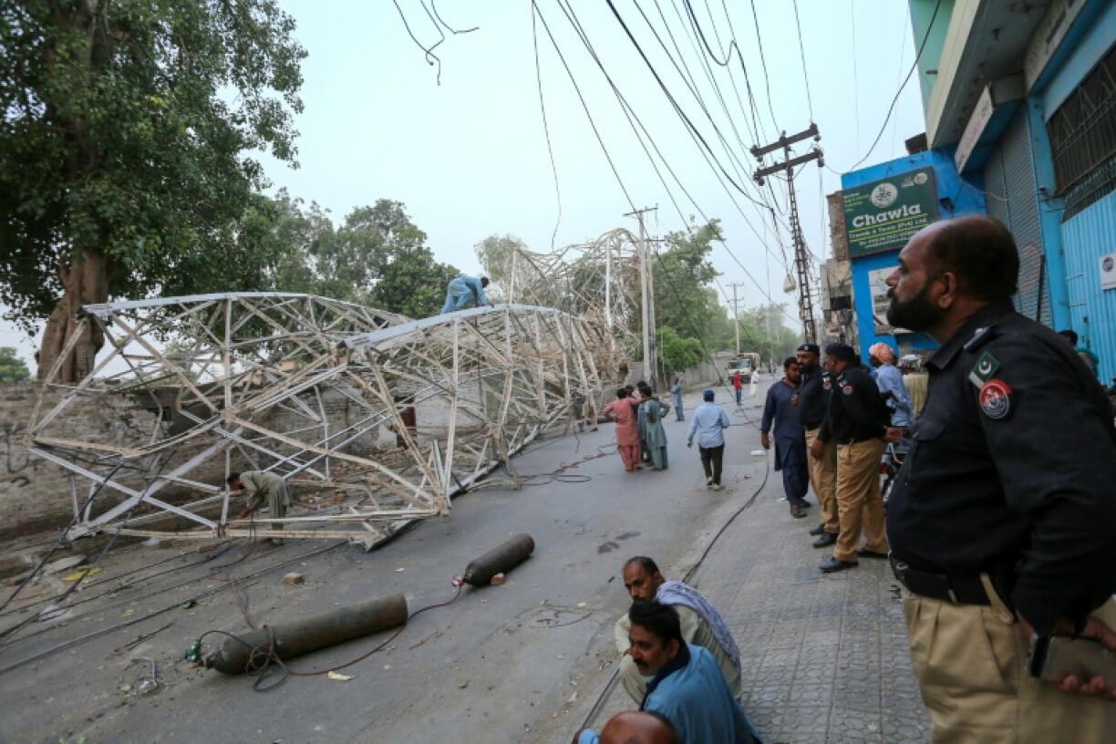A policemen looks on as workers remove a fallen tower after a violent storm in Multan, Pakistan on May 28