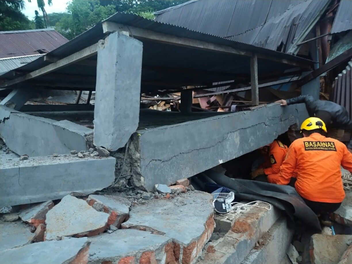 Rescuers look for survivors trapped in a collapsed building in Mamuju, the capital of Sulawesi, after the overnight quake