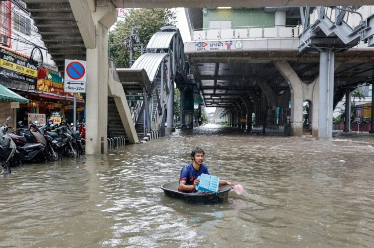 A man uses a large plastic tube to wade through floodwaters in the Bang Bua district of Bangkok