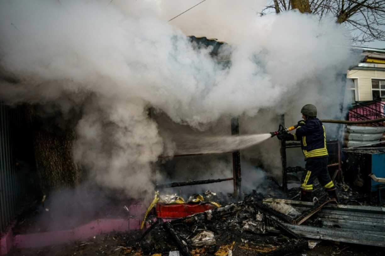 Un pompier éteint un incendie dans une boutique après une frappe russe, le 24 décembre 2022 à Kherson, en Ukraine