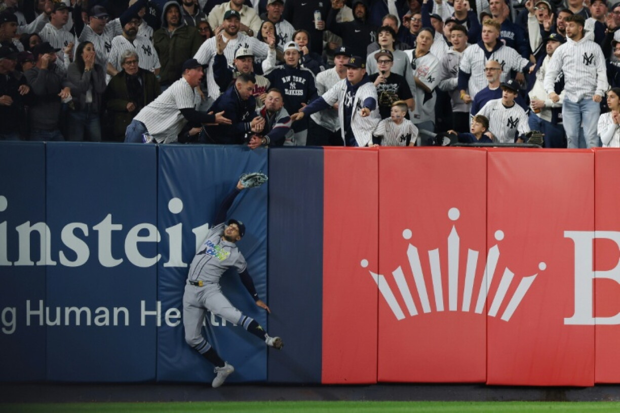 Victor Mesa Jr. of the Tampa Bay Rays is unable to make a catch as fans interfere on a ball hit by Anthony Volpe of the New York Yankees