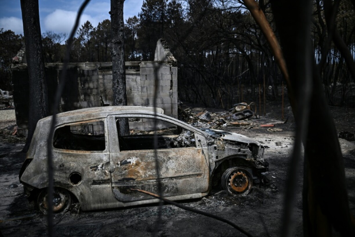 Une voiture calcinée garée devant une maison incendiée au Porge, dans le sud-ouest de la France, le 3 août 2026