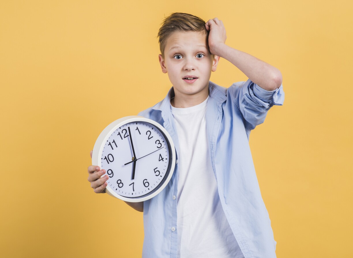 Worried boy holding clock