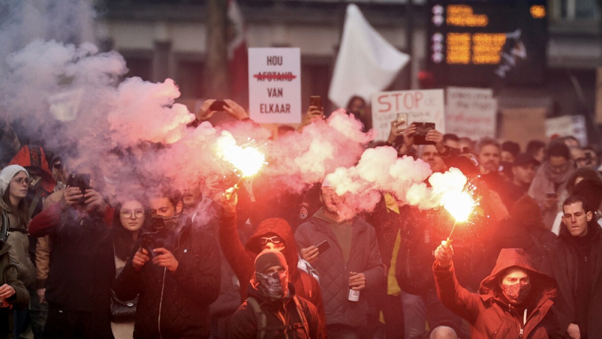 Demonstrators burn flares during a demonstration against Covid-19 measures, including the country's health pass, in Brussels on November 21, 2021.
