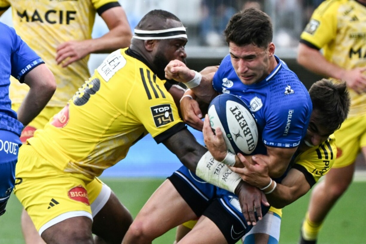 Vannes' French winger Paul Surano (C) is tackled by La Rochelle's Fijian third row Levani Botia (L) in the French Top 14 rugby union match in Brittany