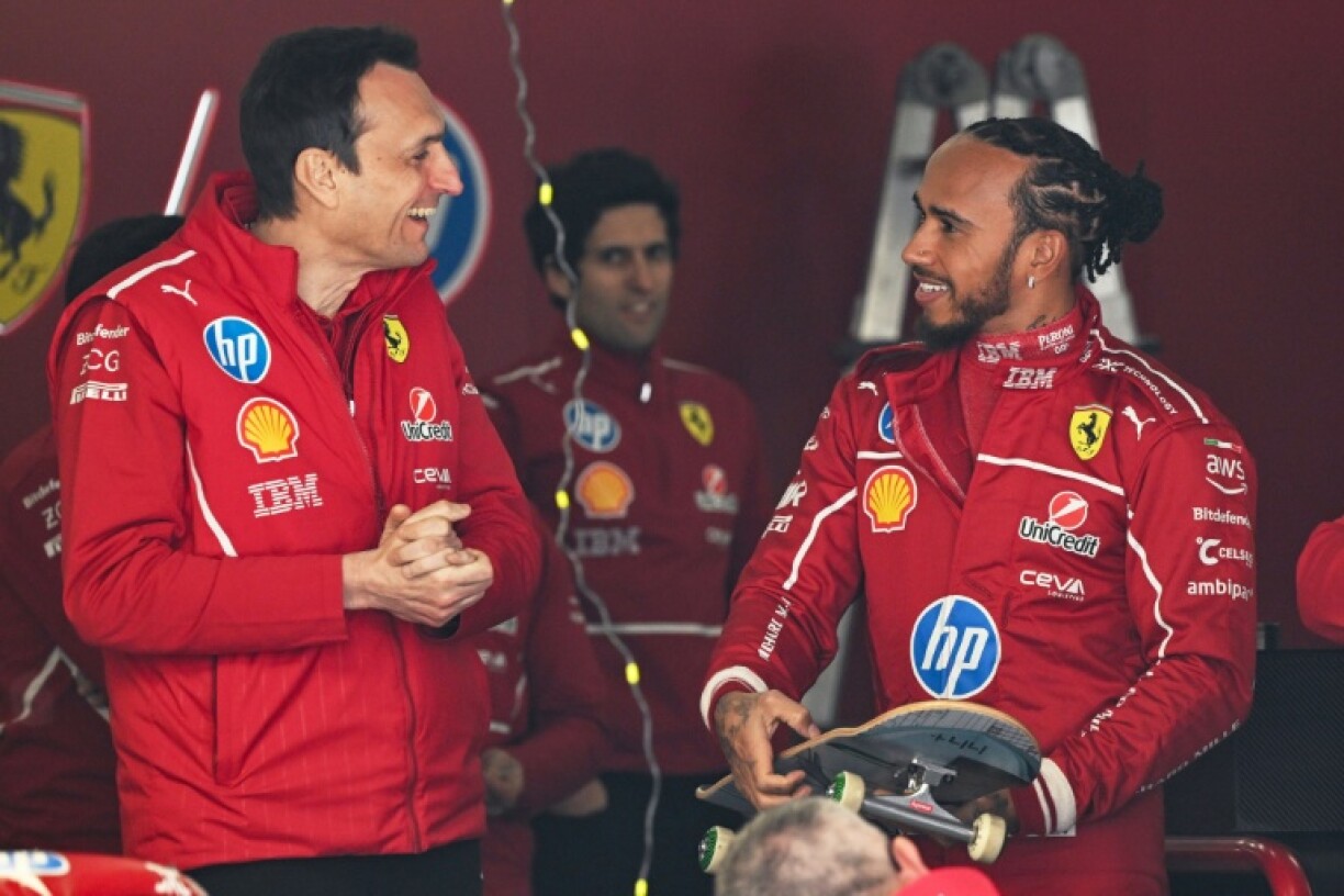 Ferrari's British driver Lewis Hamilton chats with team members while holding a skateboard in the Ferrari pit garage ahead of the Formula One Chinese Grand Prix