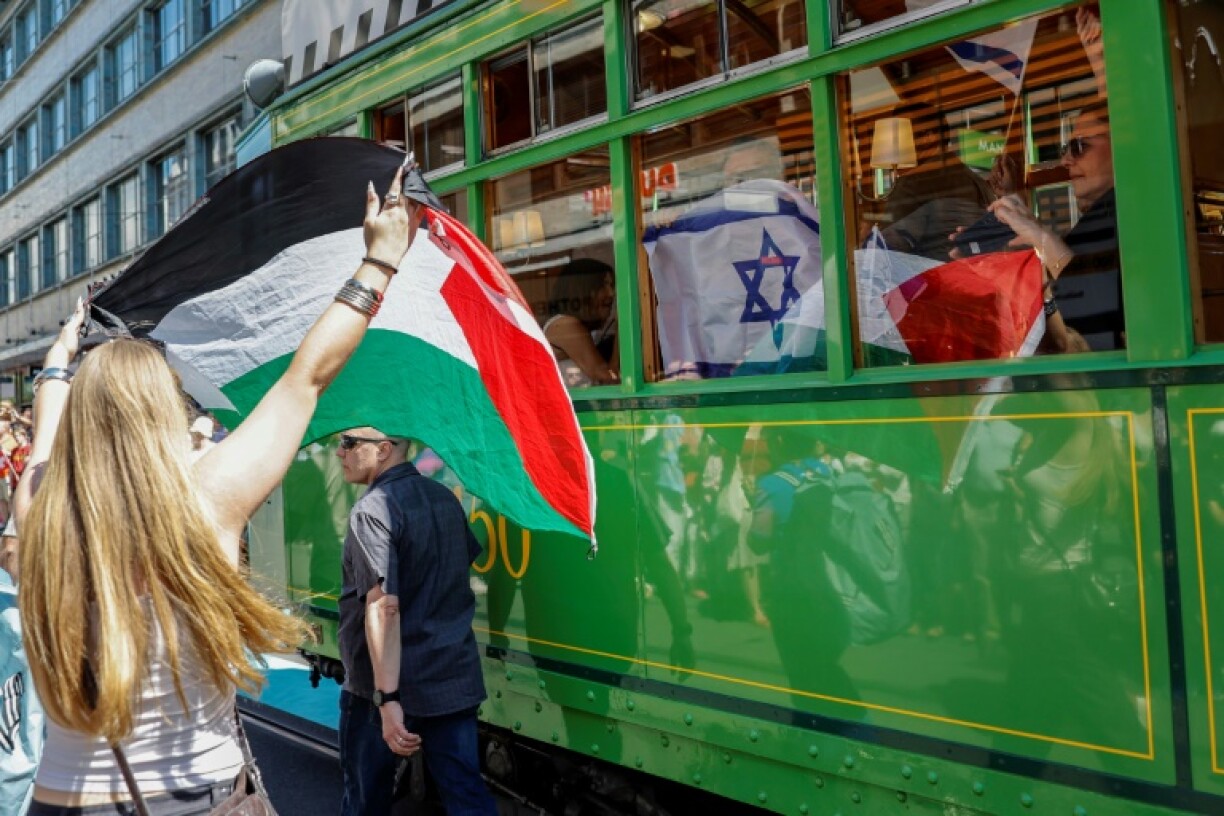 A protester holds up a Palestinian flag before the Israel delegation