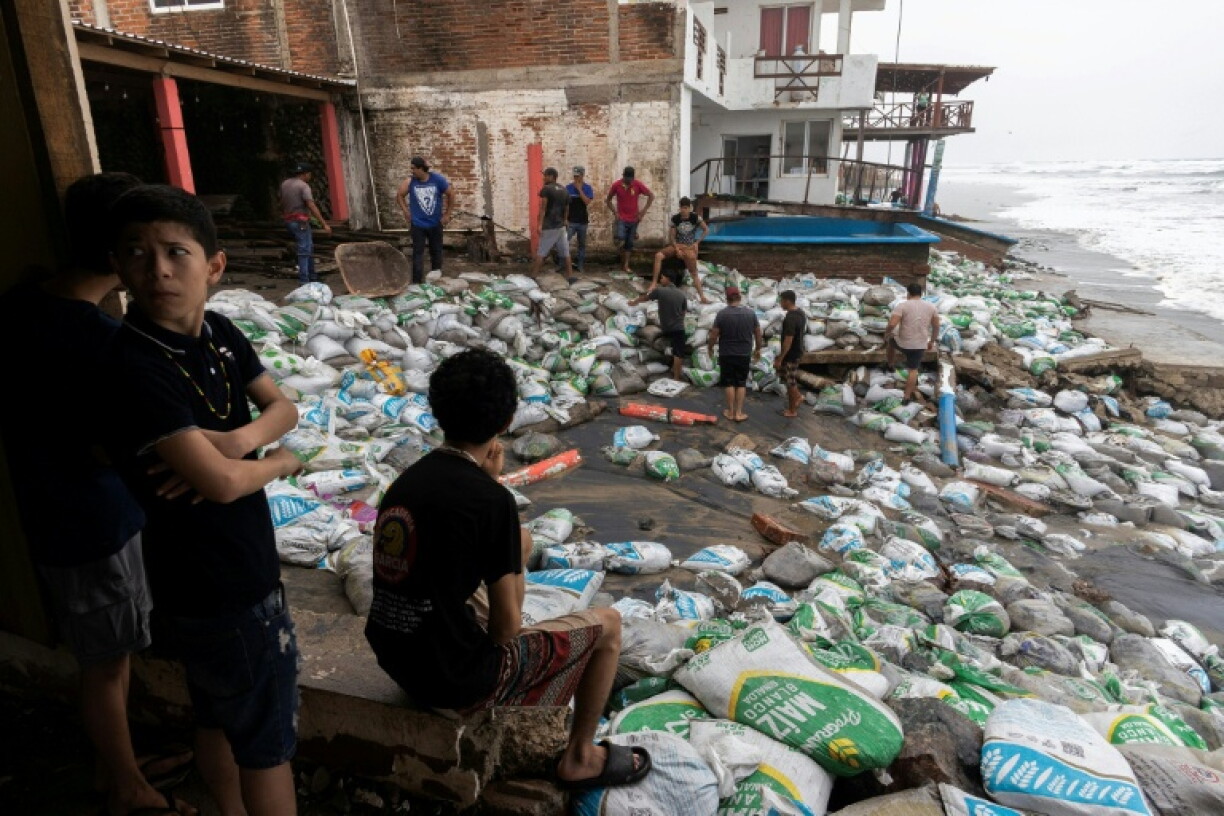 Residents place sandbags as a protective barrier against strong waves generated by Hurricane Polo in the municipality of Lazaro Cardenas, Michoacan state, Mexico
