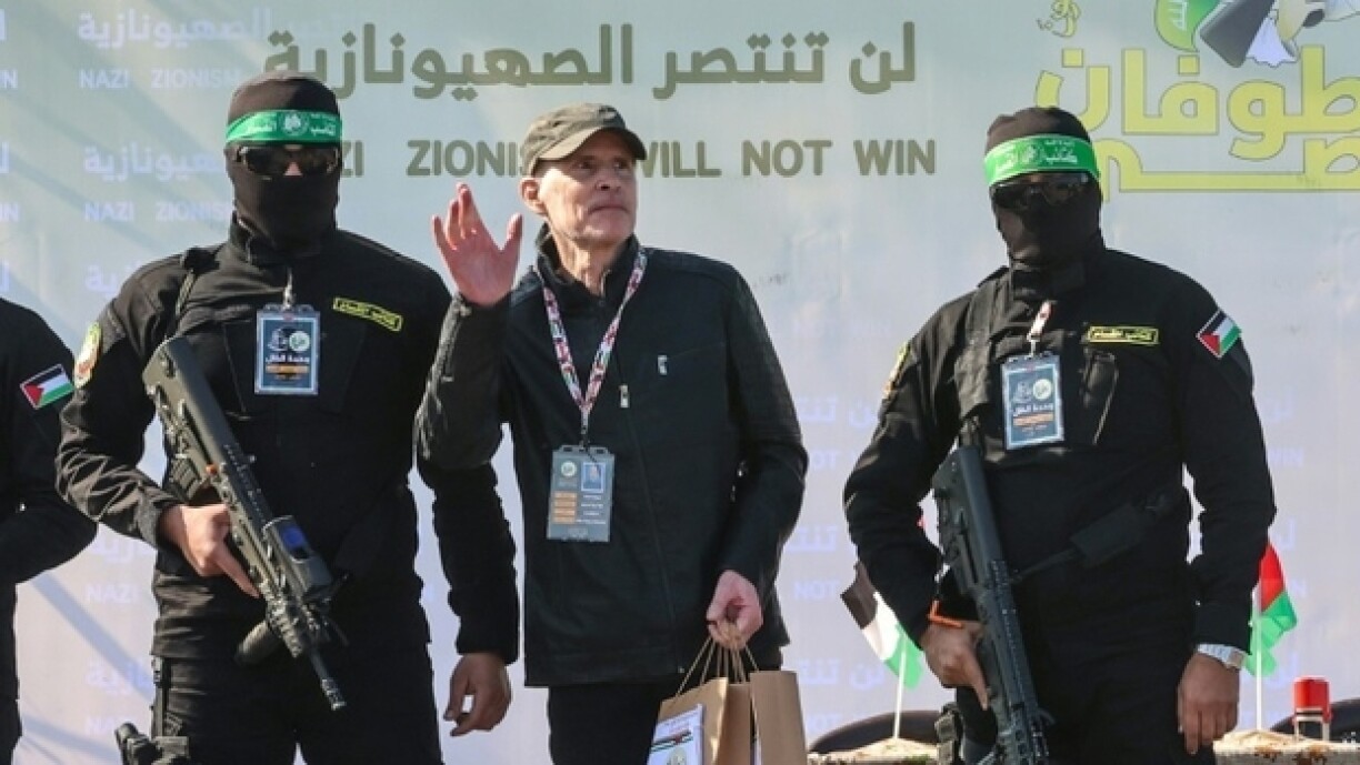 L'otage américano-israélien Keith Siegel (C) debout entre deux combattants du Hamas sur une estrade avant sa remise à la Croix-Rouge à Gaza-Ville, le 1er février 2025