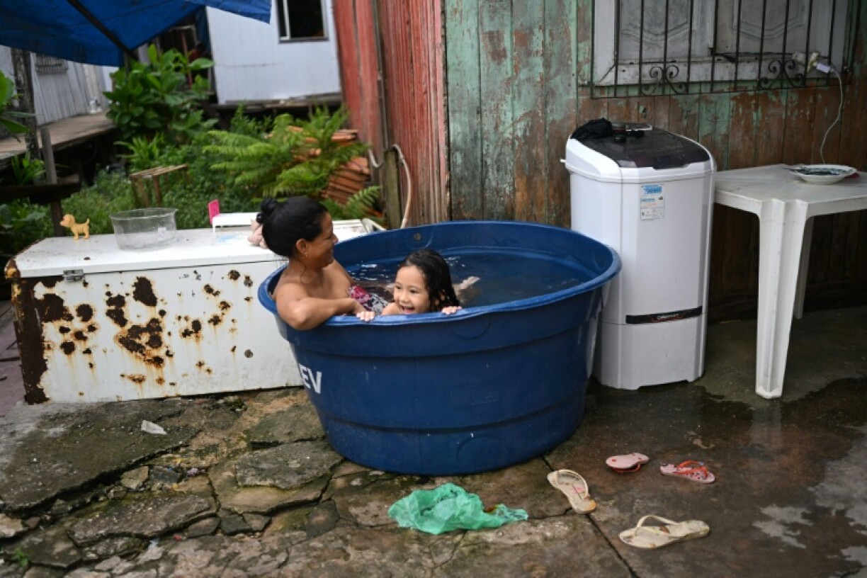 A woman and her daughter take a bath in an improvised pool at Vila da Barca, a neighborhood of stilt houses on the banks of the Guama River in Belem