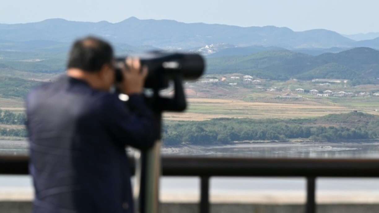 Un homme regarde la zone démilitarisée séparant la Corée du Nord de la Corée du Sud à travers des jumelles, le 9 octobre 2024 à Paju