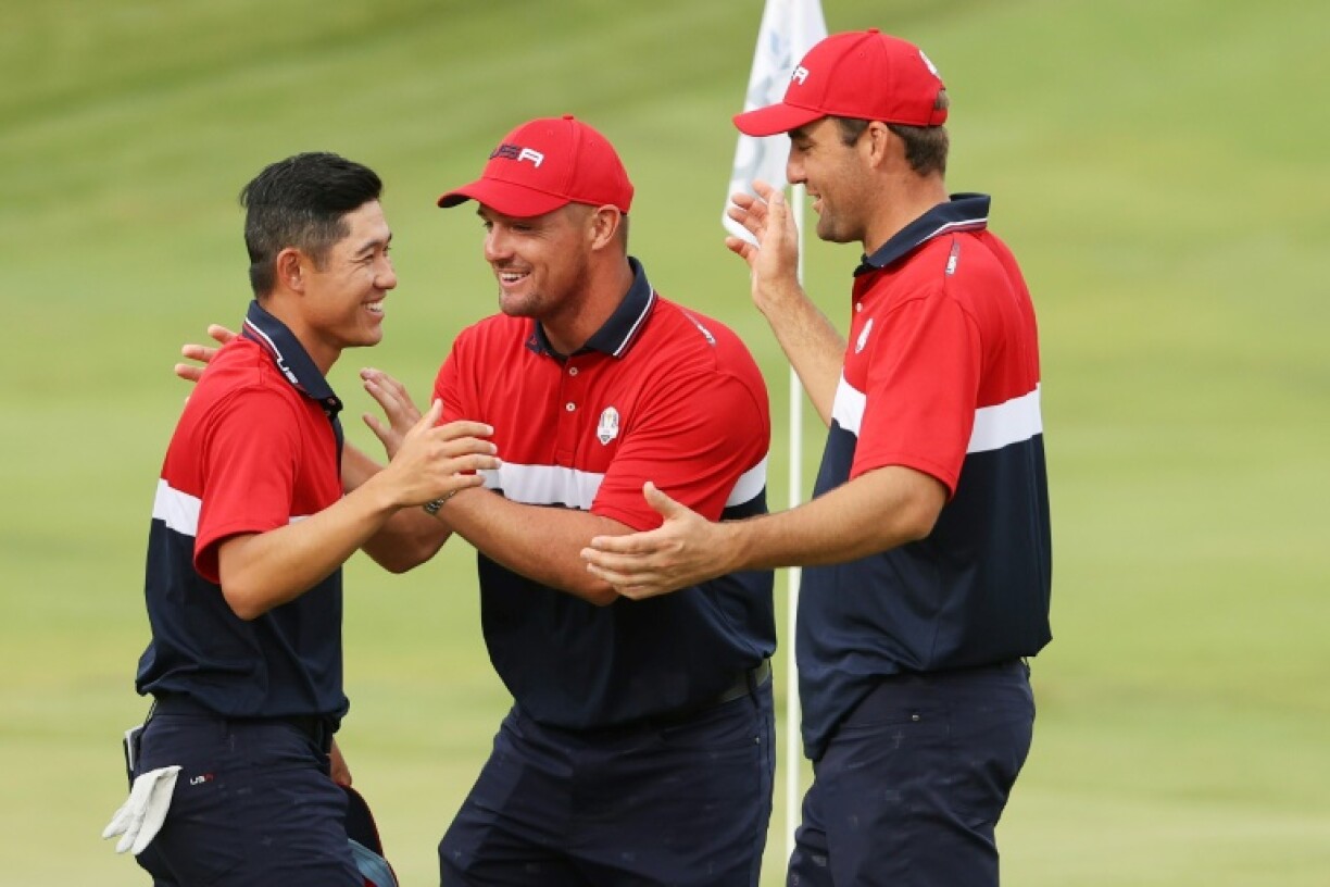 L'Américain Collin Morikawa est félicité par ses coéquipiers Bryan DeChambeau et Scottie Scheffler au 18e trou, après avoir donné le demi-point nécessaire aux Etats-Unis, victorieux de la Ryder Cup pour la 27e fois face à l'Europe, le 26 septembre 2021 sur le parcours de Whistling Straits à Kohler (Wisconsin)