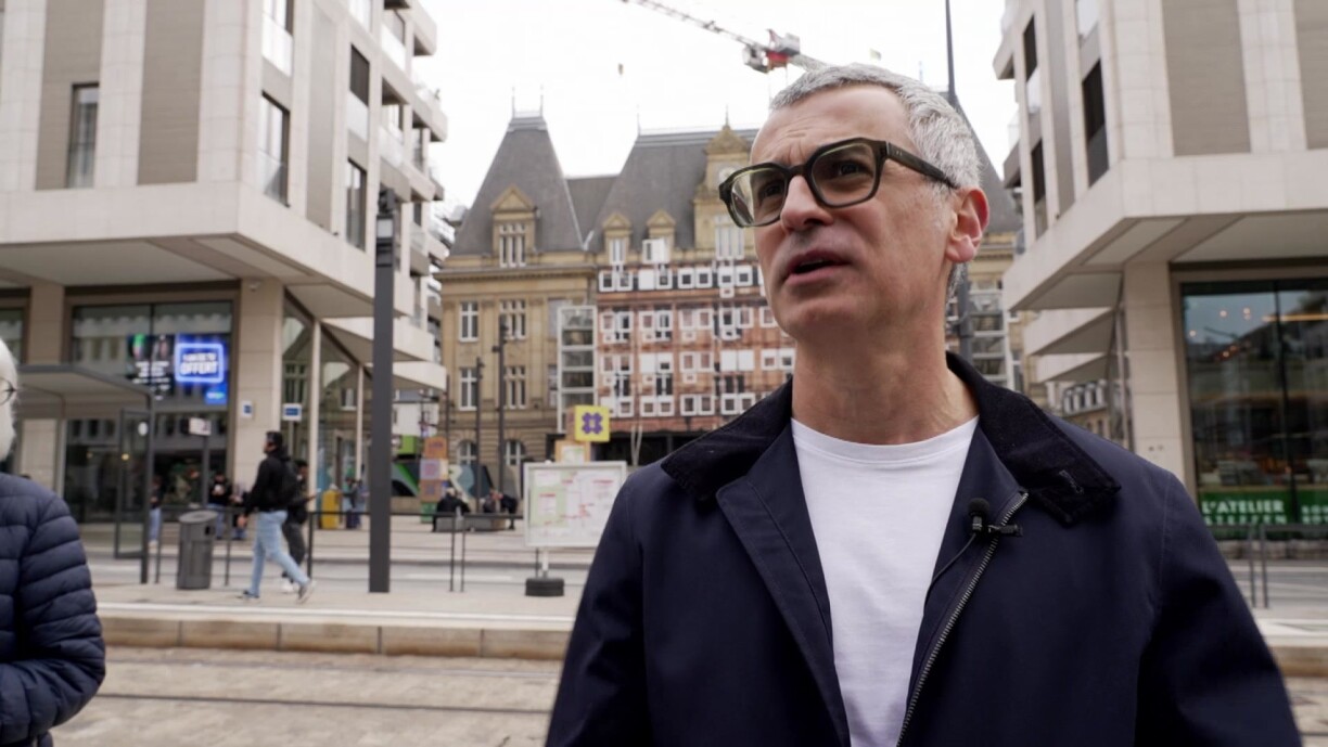Shahram Agaajani devant le Royal Hamilius, et en arrière plan l'hôtel des postes.