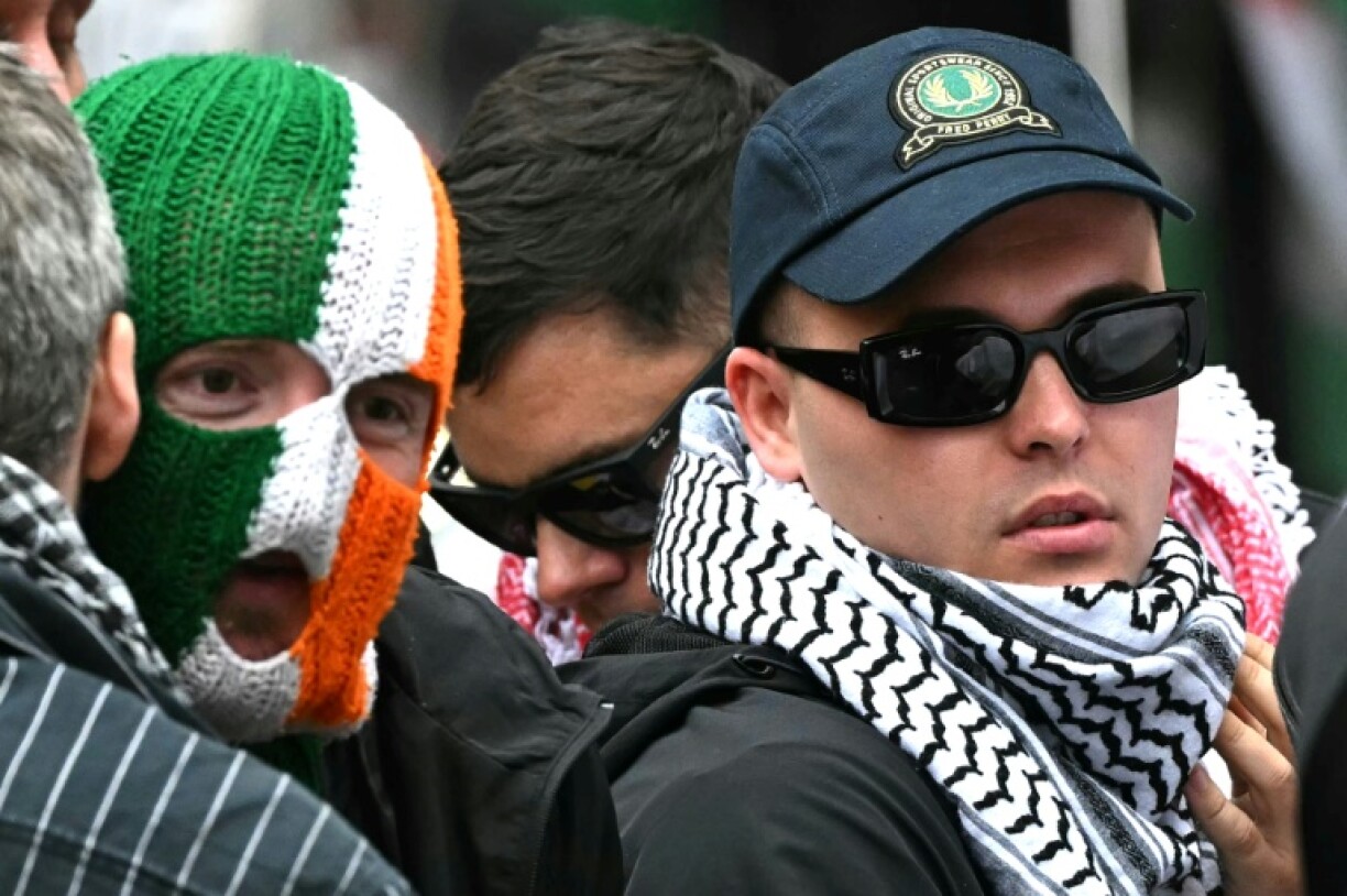 Kneecap singer Liam O'Hanna stands with bandmates Naoise O Caireallain, aka Moglai Bap (C), and JJ O'Dochartaigh, aka DJ Provai, outside Westminster Magistrates' Courts in London in August
