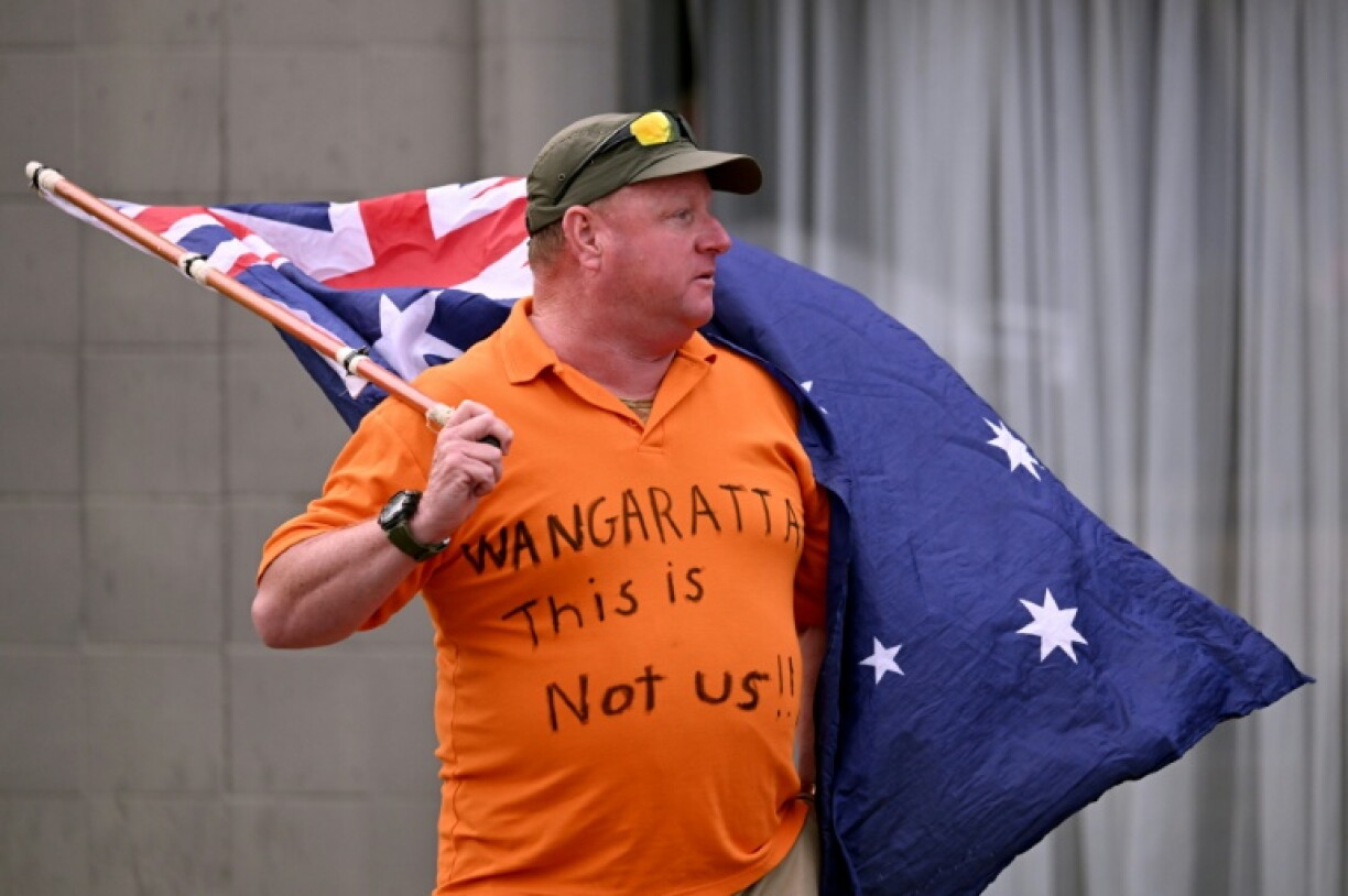 A man holds an Australian flag outside the office of Australian politician Helen Haines on October 20, 2026. The independent lawmaker Haines underwent surgery after an attack