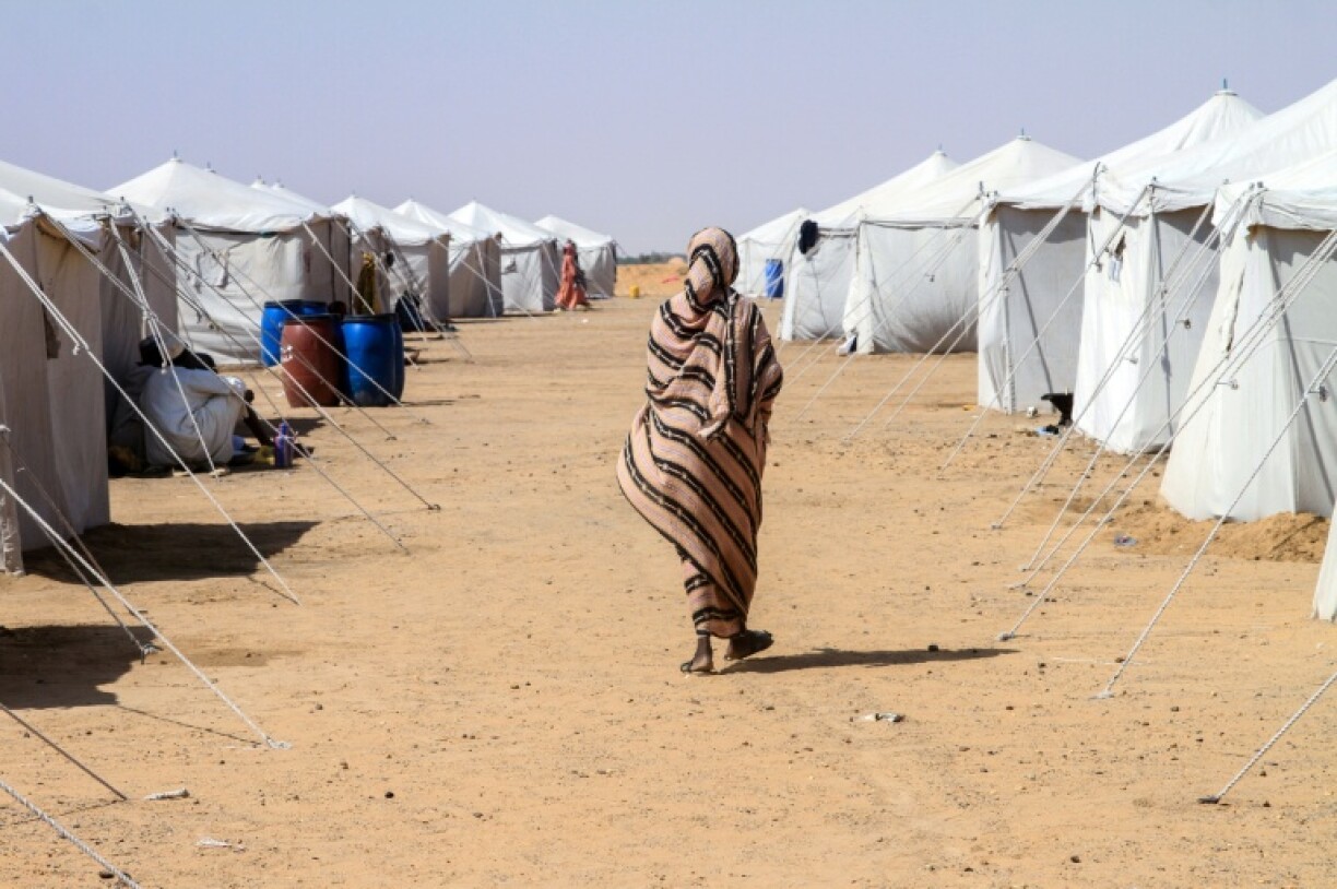 A Sudanese woman who fled El-Fasher walks past tents at Al-Dabbah refugee camp