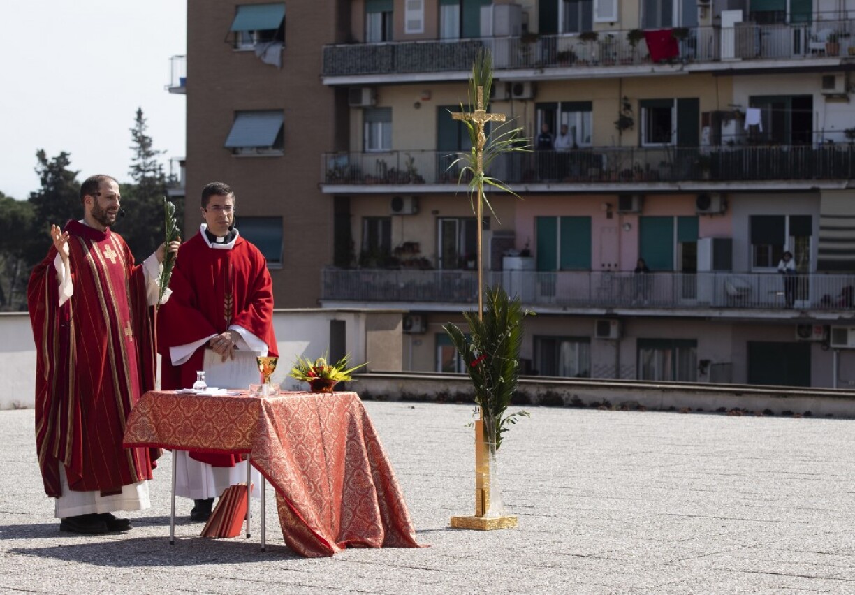 En Italie, à Rome, un prêtre célèbre la messe des Rameaux depuis le toit d'un immeuble.