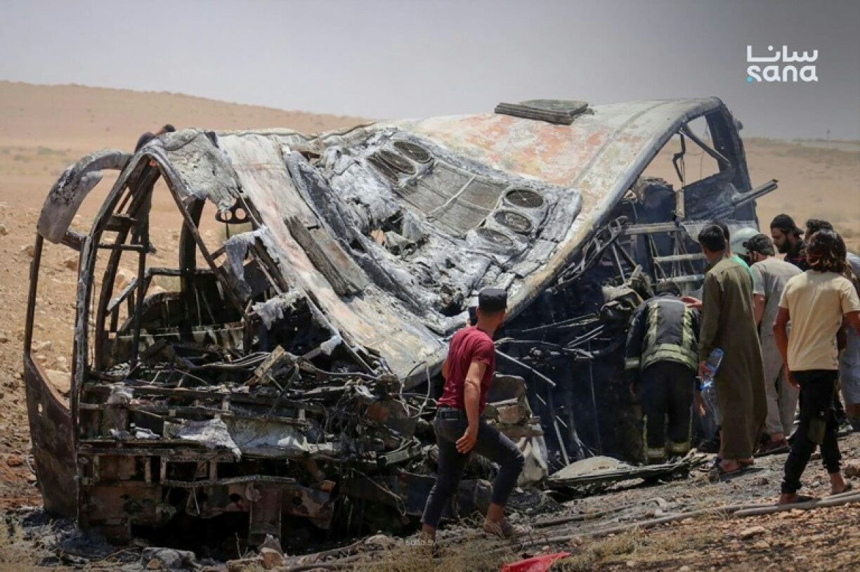 Cette photo prise et diffusée par l’agence de presse officielle syrienne SANA le 25 juillet 2026 montre des personnes et des secouristes inspectant les dégâts sur les lieux de la collision meurtrière entre deux bus sur la route reliant Damas à Deir Ezzor