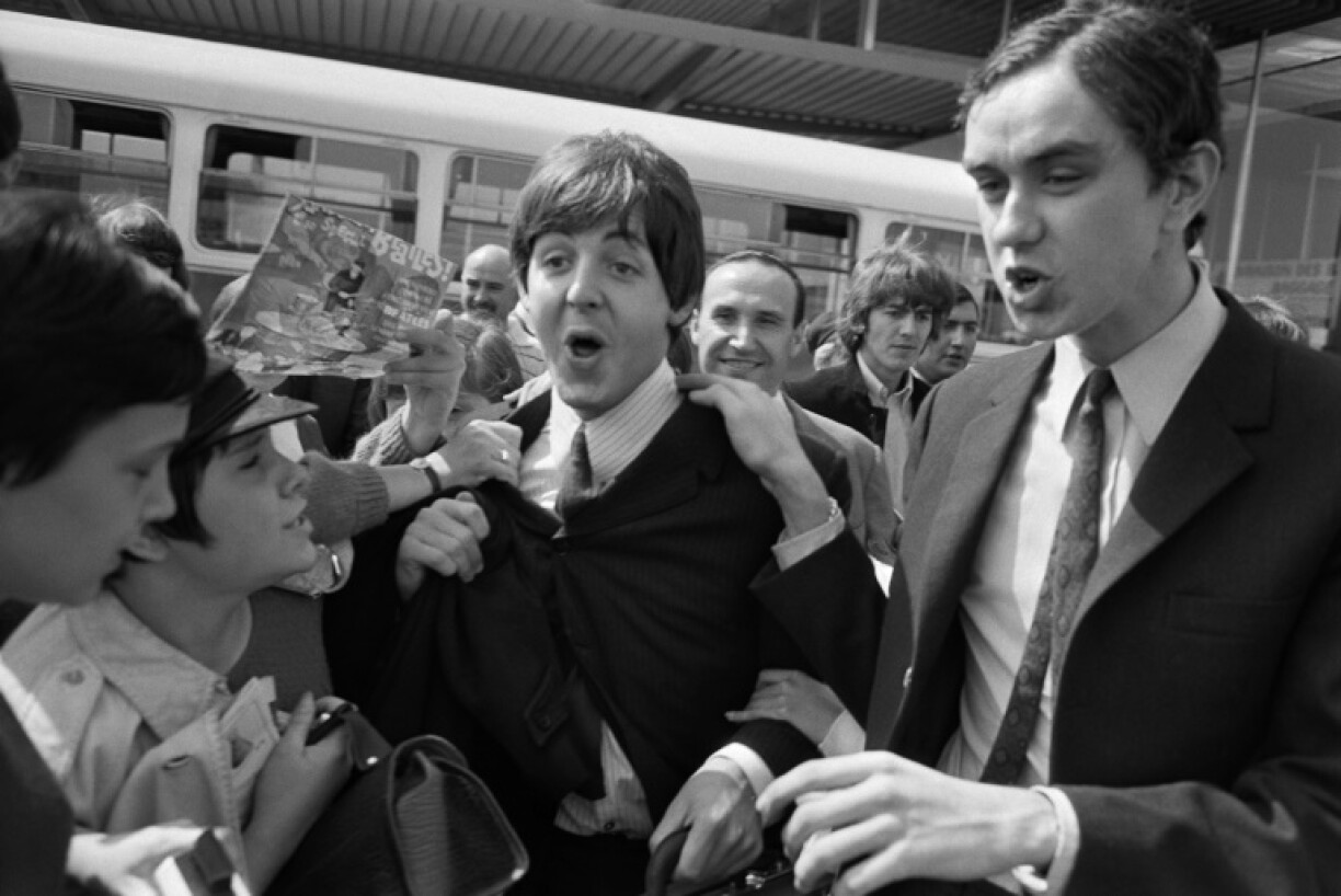 Les membres des Beatles Paul McCartney et George Harrison accueillis par des fans à leur arrivée à l'aéroport d'Orly le 20 juin 1965 avant un concert le soir-même à Paris