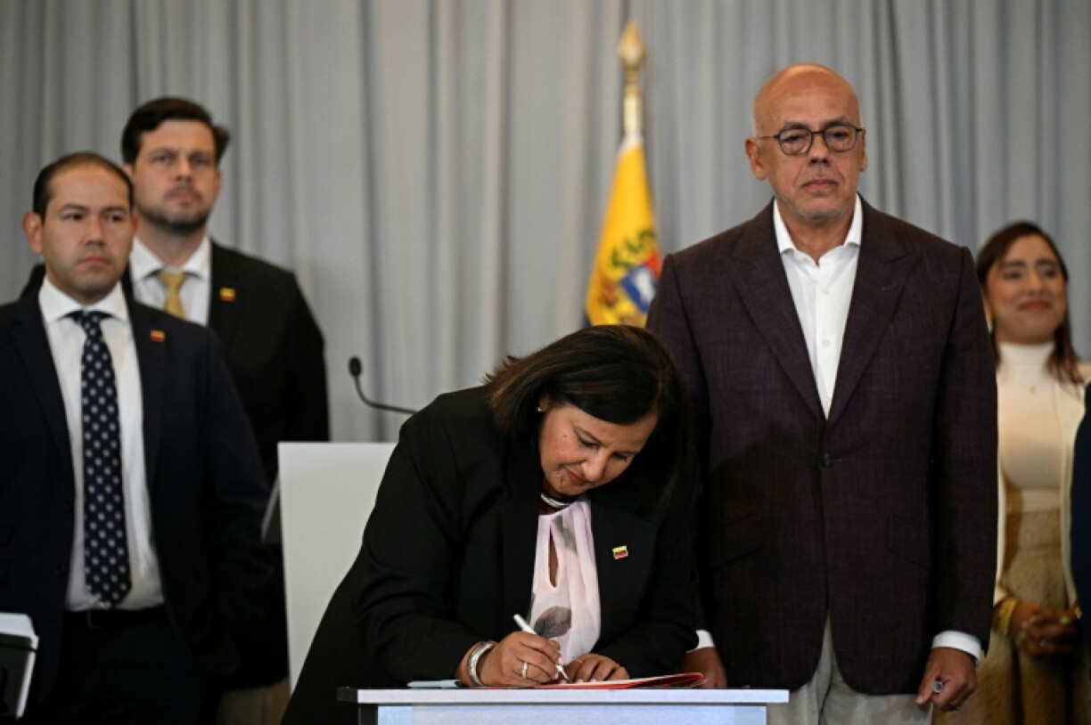 Opposition delegation head Dinorah Figuera signs an agreement as Venezuela's National Assembly President Jorge Rodriguez (R) looks on after a second round of talks in Caracas