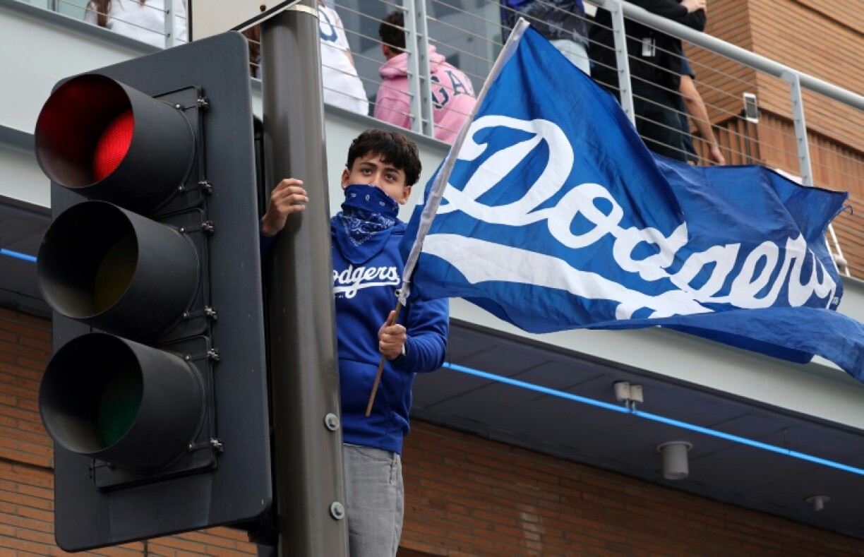 A fan applauds the Los Angeles Dodgers from on top of a street light during the team's World Series victory parade