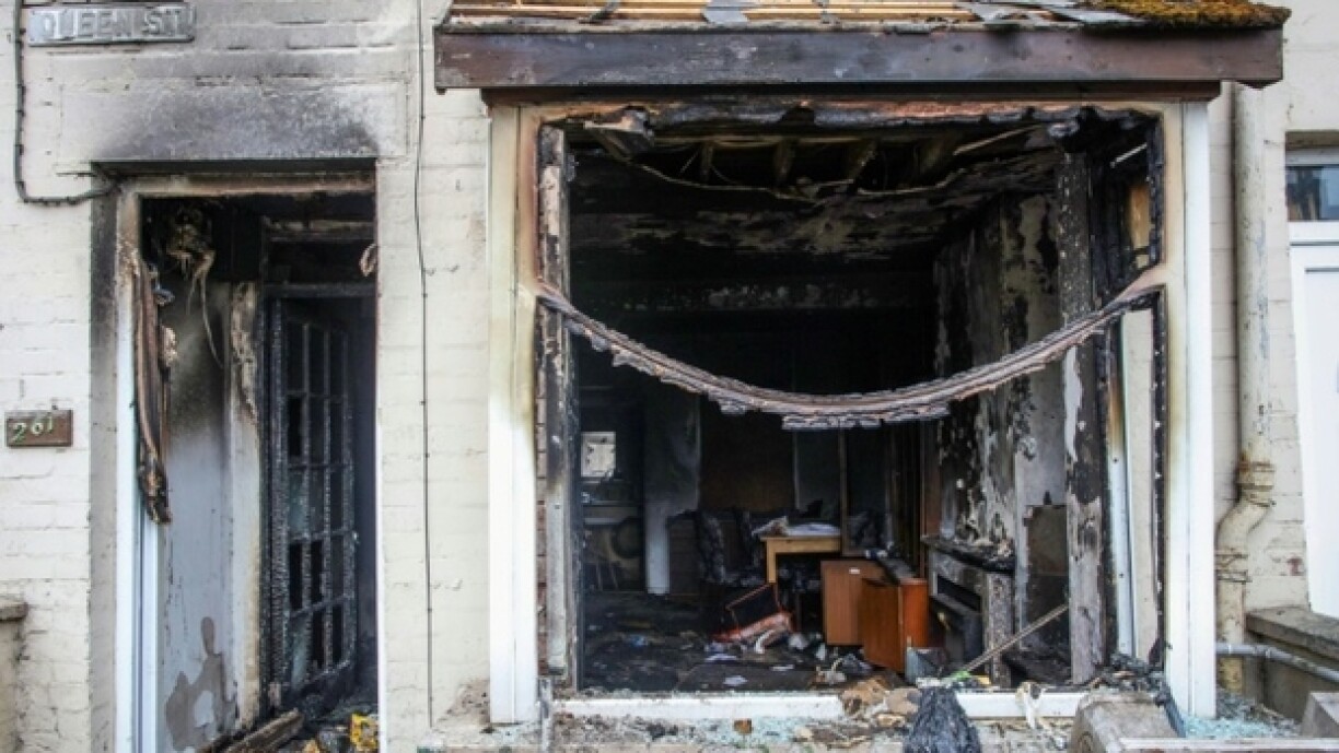 L'entrée et la fenêtre d'une maison brûlées après une deuxième nuit d'émeutes visant des immigrés à Ballymena, le 11 juin 2025 en Irlande du Nord