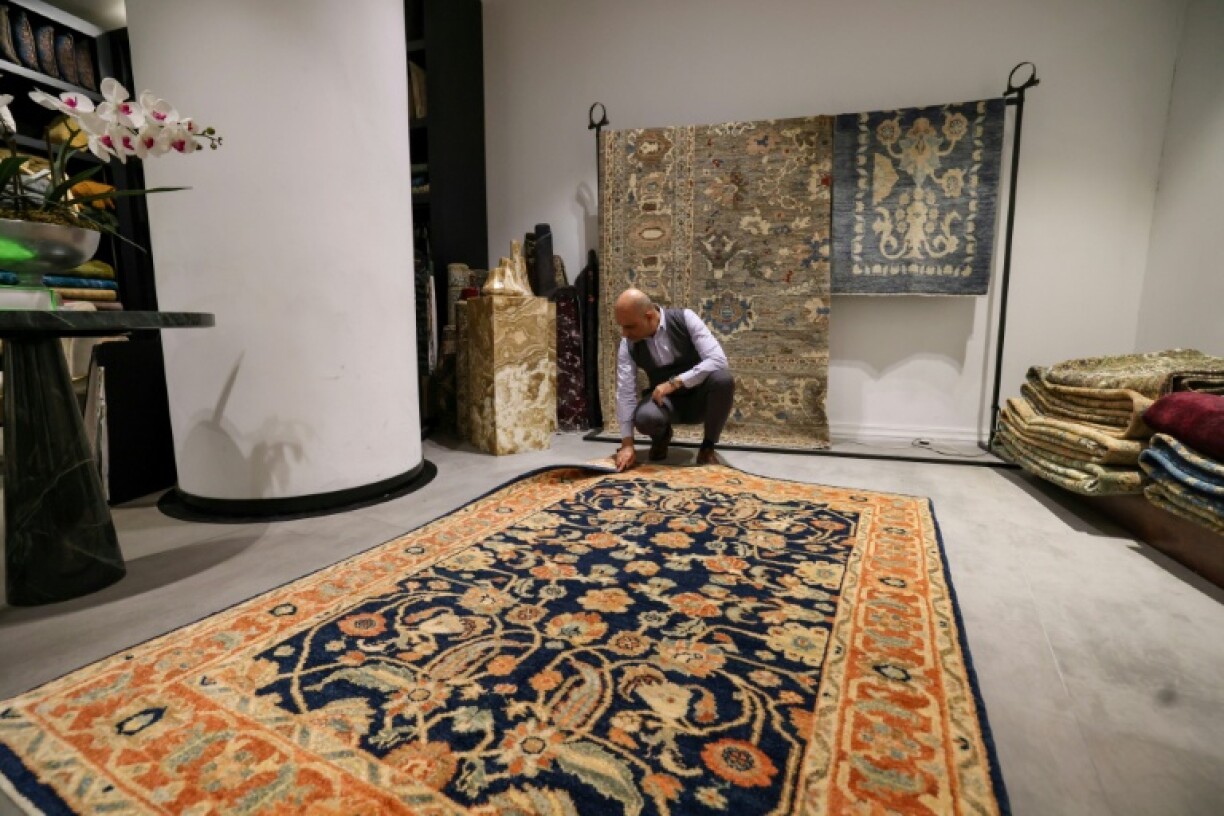 A man inspects a handmade rug in a carpet shop in northern Tehran
