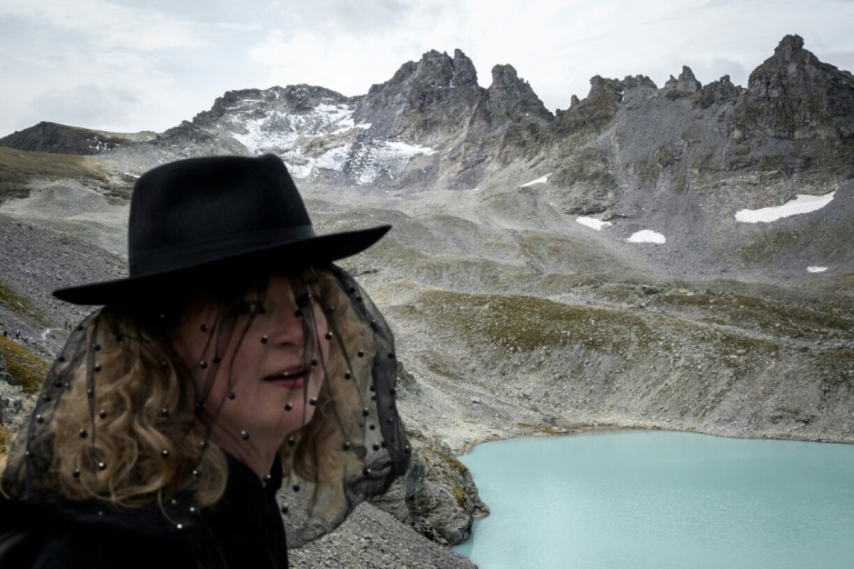 A woman looks on with the Pizol range in the background during a symbolic farewell ceremony to mark a glacier's disappearance in 2019, in eastern Switzerland.
