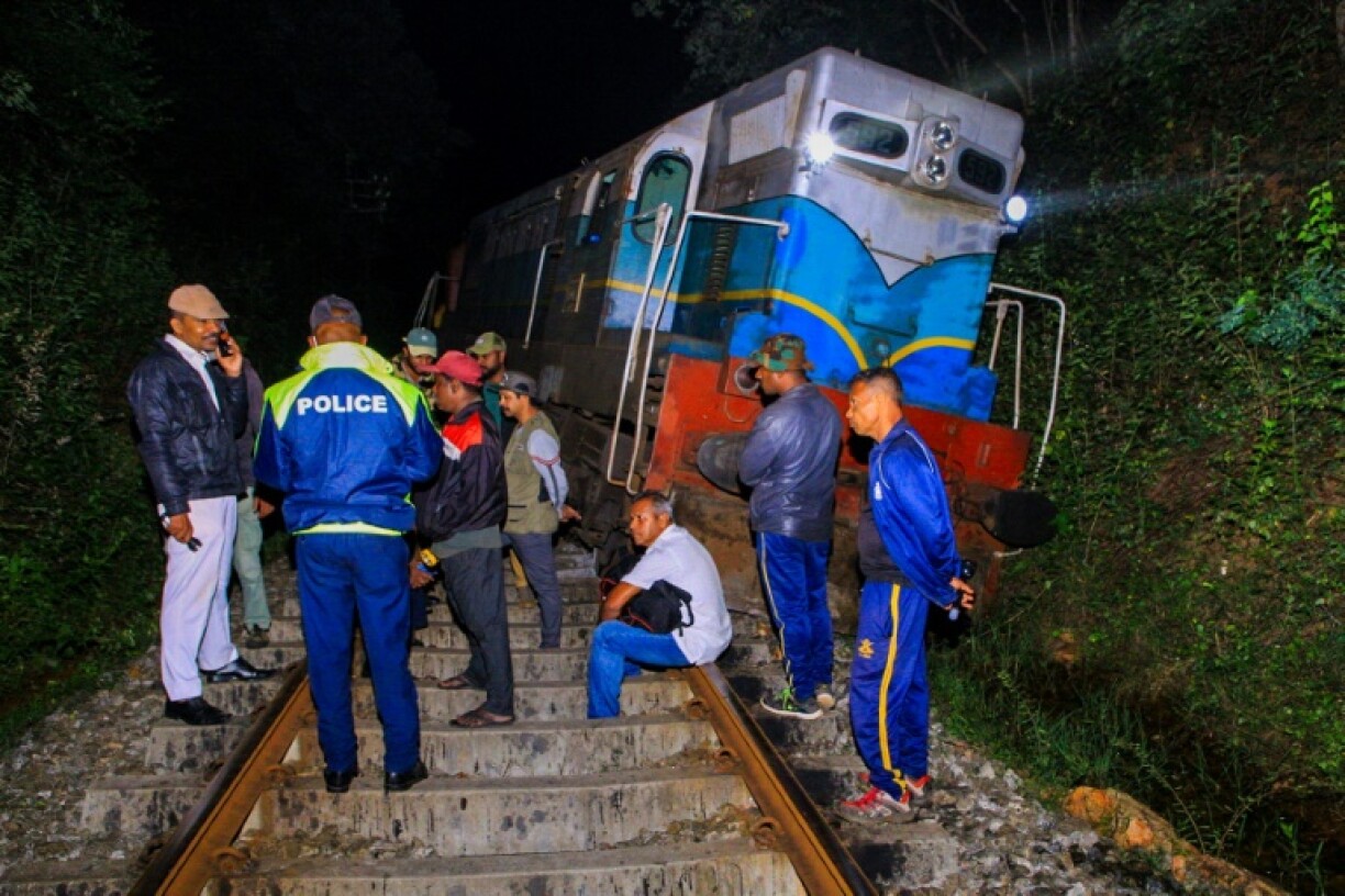 Police and railway personnel examine a derailed train at Habarana in eastern Sri Lanka