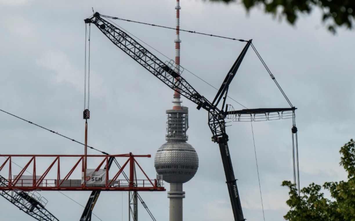 Cranes involved in the renovation of Berlin's Ostbahnhof train station operate in front of the TV Tower