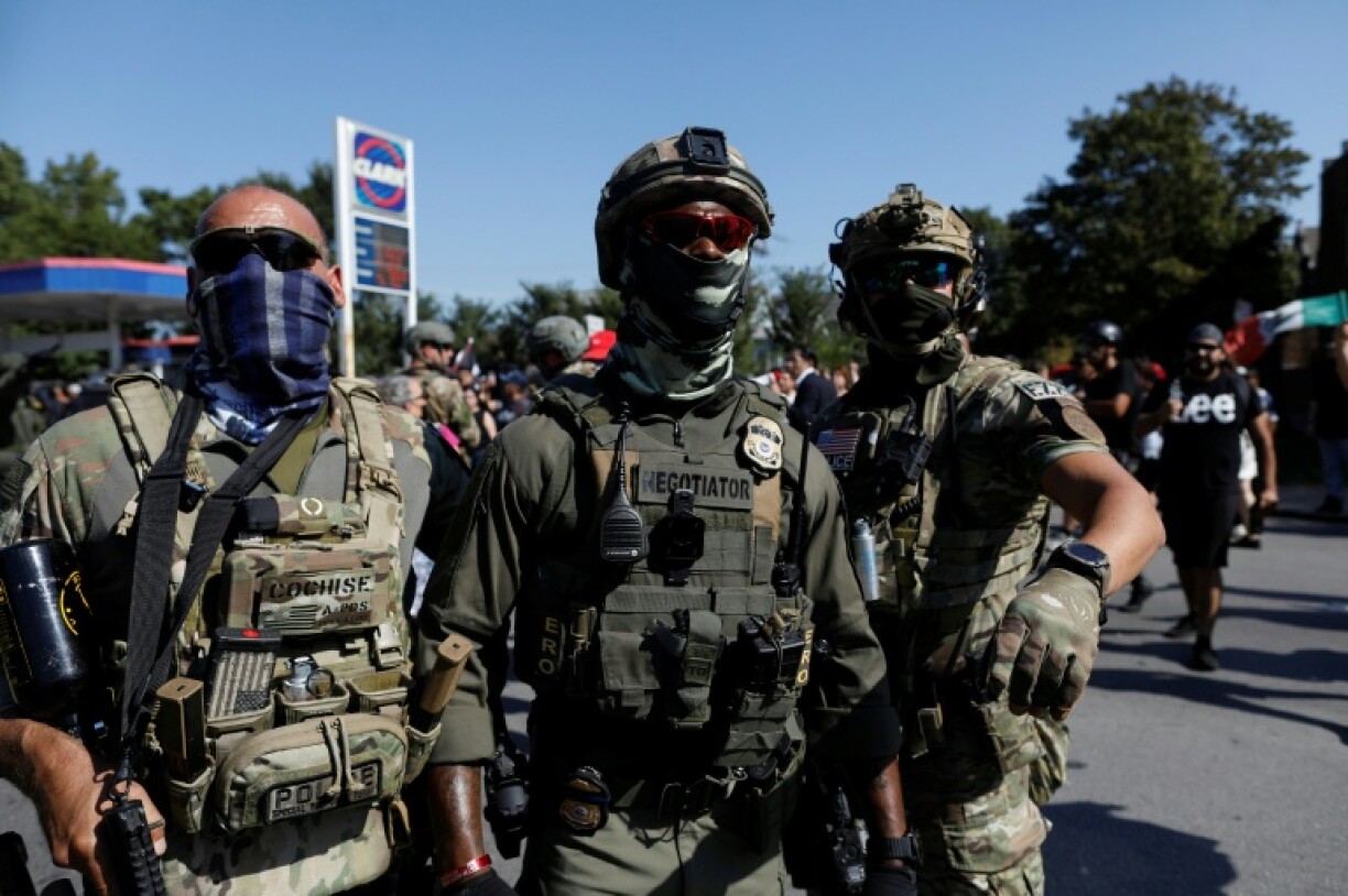 Des agents masqués de la patrouille frontalière des douanes et de la protection des frontières des États-Unis (CBP) derrière cordon de police à Chicago, le 4 octobre 2025 dans l'Ilinois