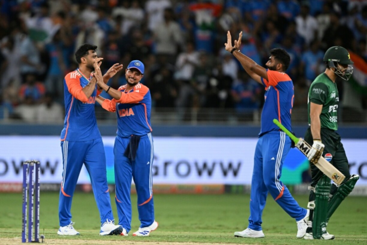 Pakistan captain Salman Agha (R) walks back to the pavilion after his dismissal by Axar Patel (L)