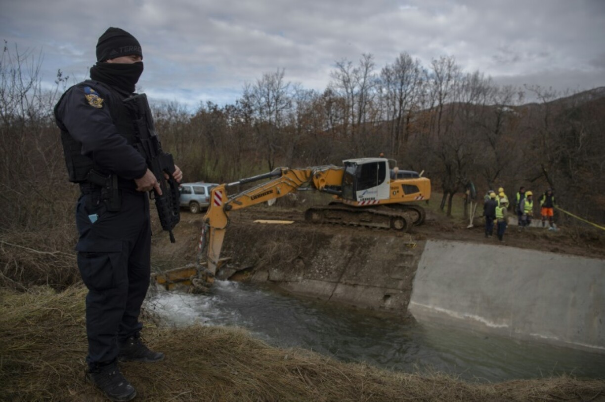 Kosovo police stand next the site of a blast on a vital canal, as workers attempt to repair the damage