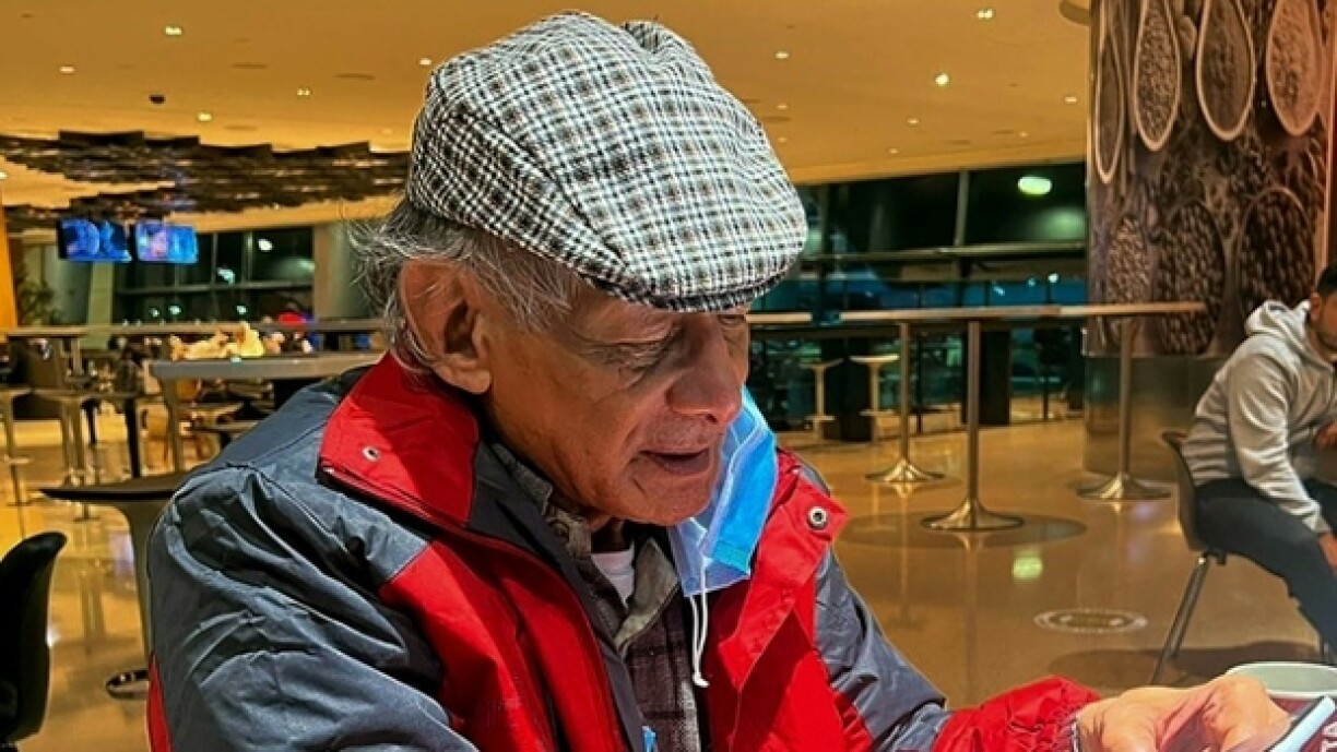 Le tueur en série français Charles Sobhraj consulte son smartphone à l'aéroport de Doha, où il est en transit, le 23 décembre 2022 au Qatar