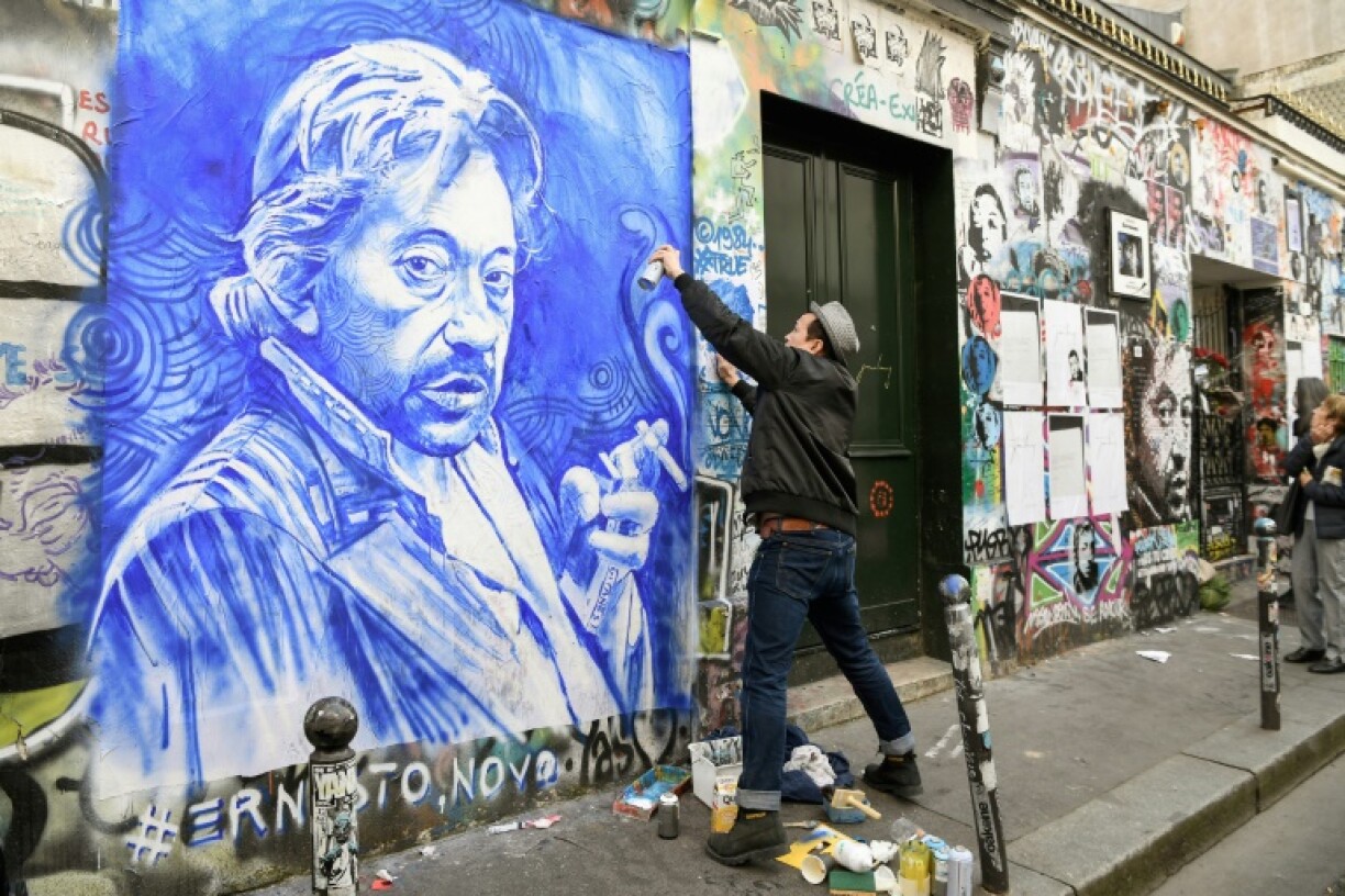 Le peintre français Ernesto Novo réalise un portrait de Serge Gainsbourg sur la façade de la maison de l'artiste, le 2 mars 2021 à Paris